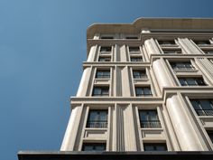 a tall building with balconies on the top and bottom floors against a blue sky