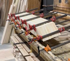 several pieces of wood being worked on in a shop with red and orange tools attached to them