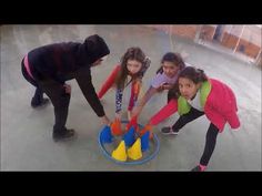 three girls are playing with plastic cones on the floor and one girl is looking at them