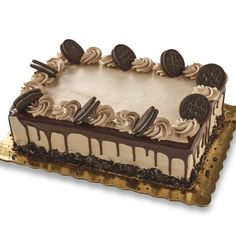 an oreo cookie cake with cream frosting and chocolate cookies on top, sitting on a gold platter