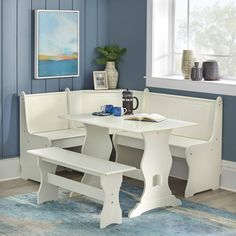 a white table and bench in a room with blue walls, rugs and pictures on the wall