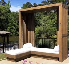 a wooden bench sitting next to a white couch on top of a cement slab in front of a lake