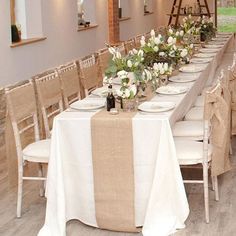 a long table is set with white flowers and place settings