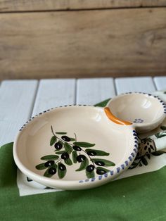 two ceramic olives are sitting on a green napkin next to a wooden tablecloth