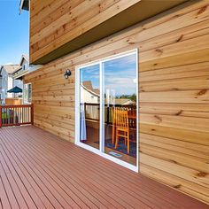 a wooden deck with sliding glass doors and chairs