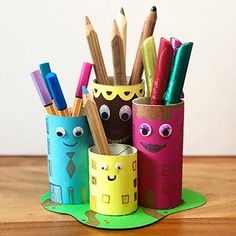 some pencils and markers are in a cup on a wooden table with other items