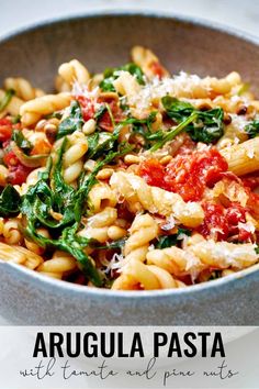 a bowl filled with pasta and spinach on top of a table