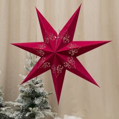 a red origami star hanging from the ceiling next to a small christmas tree