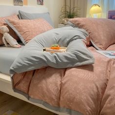 a bed with pink comforters and pillows on it