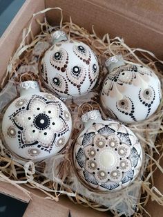 four ornaments are in a box on the floor and one is decorated with black and white designs