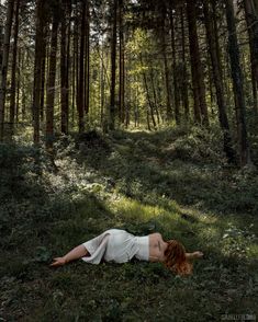 a woman laying on the ground in front of trees