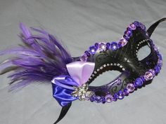 "\" This is a made to order mask, yours will be similar to the one shown\" Intricate black base is accented with purple glitter for added sparkle.  Features feathers topped off with purple ribbon and a silver and rhinestone flower as the centerpiece. Mask is attached to ribbons for ease in hands free wearing, perfect for the bride, bridesmaid or party girl.  Want to see other masquerade masks? Click Here http://www.etsy.com/shop/thecraftychemist07?section_id=7175692 Contact me for a custom order Purple Masquerade Mask For Mardi Gras, Purple Masquerade Mask For Mardi Gras Carnival, Purple Eye Mask For Costume Party, Purple Masquerade Mask For Carnival, Purple Masquerade Mask, Elegant Masquerade Mask, Mascarade Party, Masquerade Mask Diy, Black Masquerade Mask