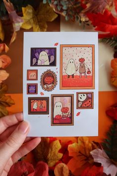 a hand holding up a card with pictures of halloween characters and pumpkins on it