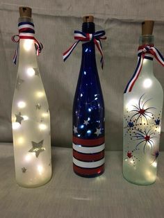 three wine bottles with lights on them sitting next to each other