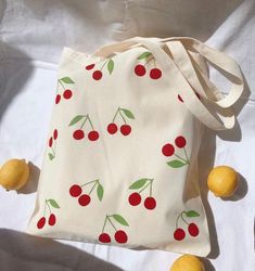 a white bag with cherries on it and three lemons next to the bag