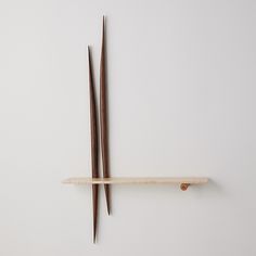 two chopsticks hang on the wall next to a shelf with sticks sticking out of it