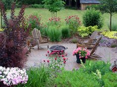 a garden with lots of flowers and chairs in the center, surrounded by trees and shrubs