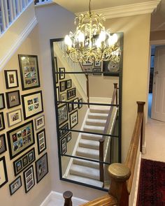 a staircase with pictures on the wall and chandelier