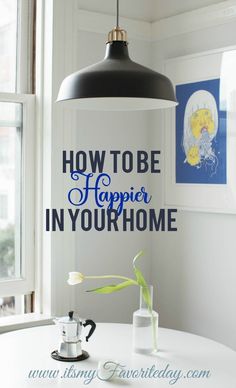 a white table with a black lamp hanging over it and the words how to be happy in your home