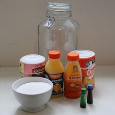 an assortment of food items sitting on a counter next to a glass jar with liquid in it