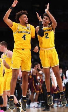 two michigan basketball players jumping in the air