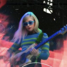 a woman with blue sunglasses is playing the guitar