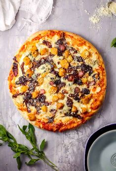 a pizza sitting on top of a table covered in cheese and toppings next to a bowl