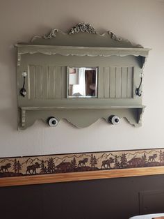 a mirror mounted to the side of a wall next to a shelf with hooks on it