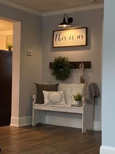 a white bench sitting in the middle of a living room next to a wall mounted sign