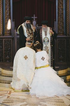 the bride and groom are kneeling down in front of the priest, who is holding his head