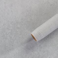 a rolled up piece of paper sitting on top of a cement floor next to a cup