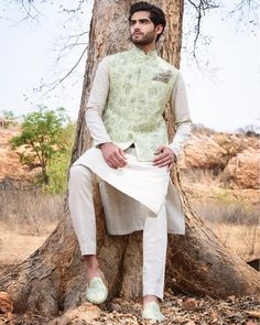 a man sitting on top of a tree in front of a tree wearing a white suit