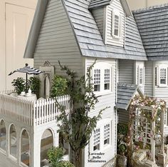 a doll house with lots of windows on the front and side of it, next to a potted plant