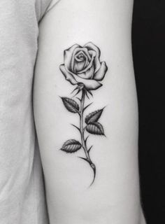 a black and white photo of a rose tattoo on the left side of the thigh