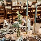 the table is set with silverware and flowers in vases, napkins and candles