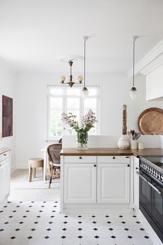 a white kitchen with black and white tile flooring, an oven and counter tops