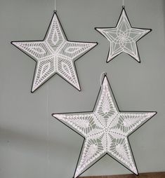 three white stars are hanging from the ceiling and one has a spider web design on it