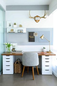 a desk with some drawers and a chair in front of it, next to a wall mounted deer head