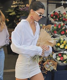 a woman in white shirt and shorts holding flowers