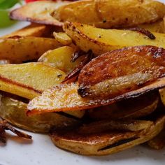 some fried potatoes on a white plate with herbs and seasoning next to the side