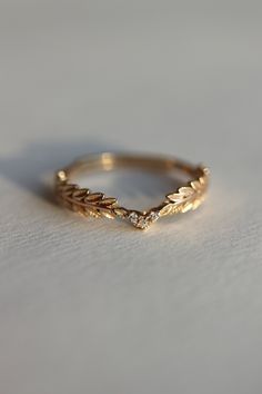 a gold wedding band with leaves on the side and a diamond set in the middle