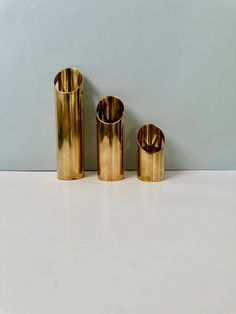 three brass vases sitting on top of a white counter