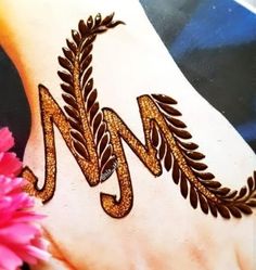 a henna tattoo is on the foot of a woman with pink flowers in front of her