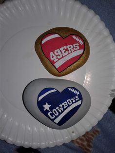 two heart shaped cookies sitting on top of a paper plate next to another cookie in the shape of a cowboy's heart