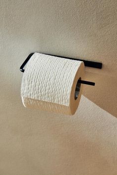 a roll of toilet paper is hanging on the wall next to a black handle that holds it in place