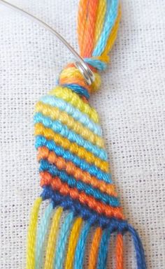 a multicolored piece of yarn with a metal hook on the end that has been stitched together