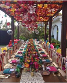 a long table with many plates and place settings on it, decorated with colorful flowers