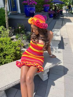 a woman in a colorful dress sitting on a bench