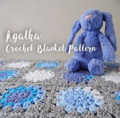 a crocheted blanket with a blue bunny sitting on it