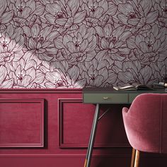 a pink chair sitting next to a desk in front of a wall with flowers on it